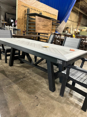 Harmony Outdoor Table by Wooden Whale Workshop with a gray slatted top and black frame in a warehouse showroom