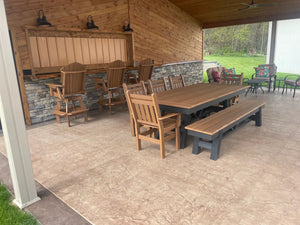 Harmony Outdoor Table with wooden benches and chairs on a covered patio in a natural brown wood finish