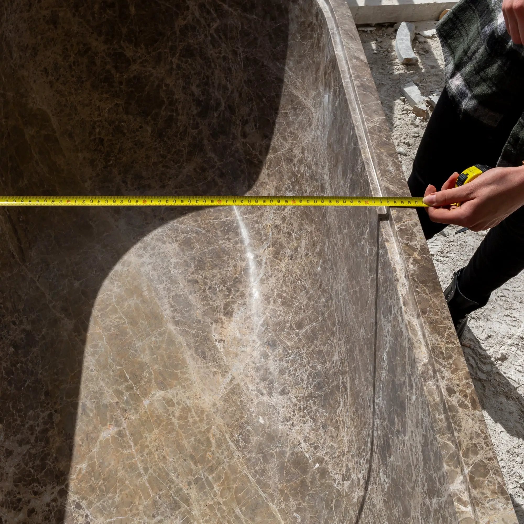 Emperador Light Marble Bathtub with solid brown-veined marble and curved rim, photographed with a measuring tape.