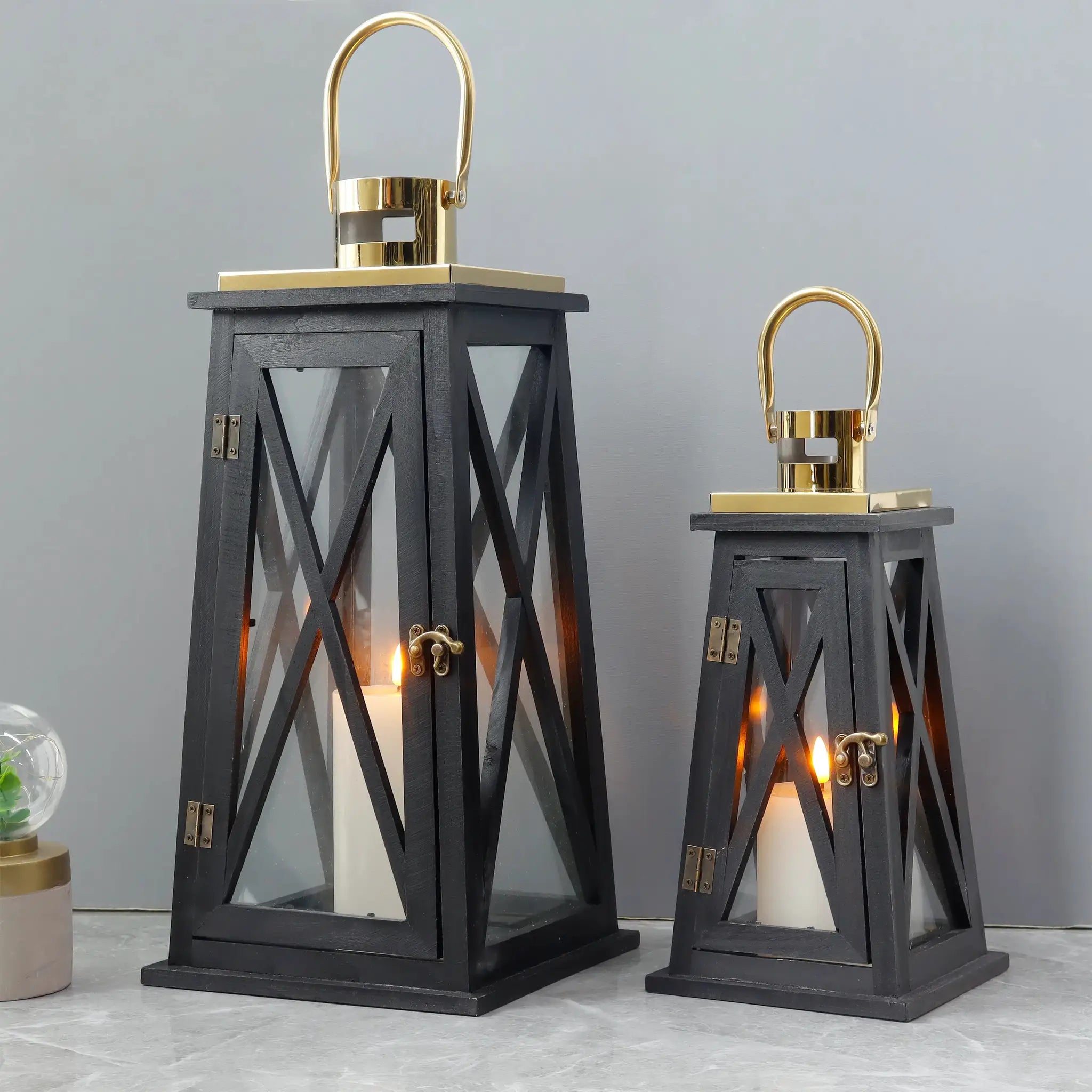 Set of 2 farmhouse wooden decorative candle lanterns, black trapezoid, 12in and 18in tall with gold metal trim.