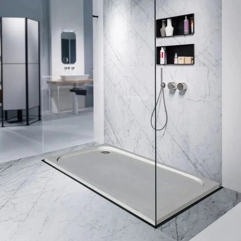 Shell Stone limestone shower base, rectangular hand-carved from solid block; 36x48 inches in a glass-enclosed shower.