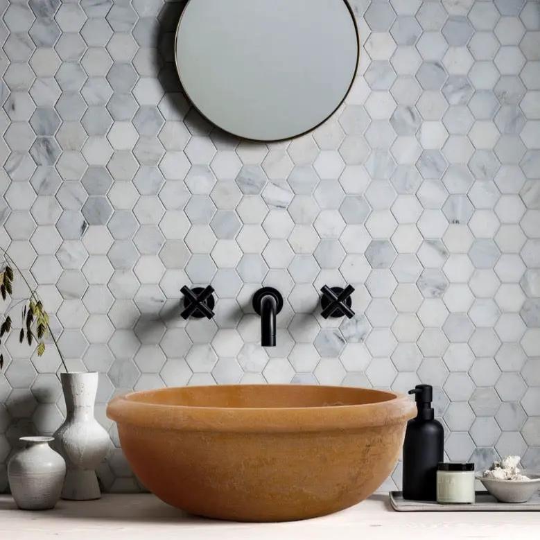 Golden Sienna travertine vessel sink by Villohome on bathroom vanity with black wall faucet and round mirror.