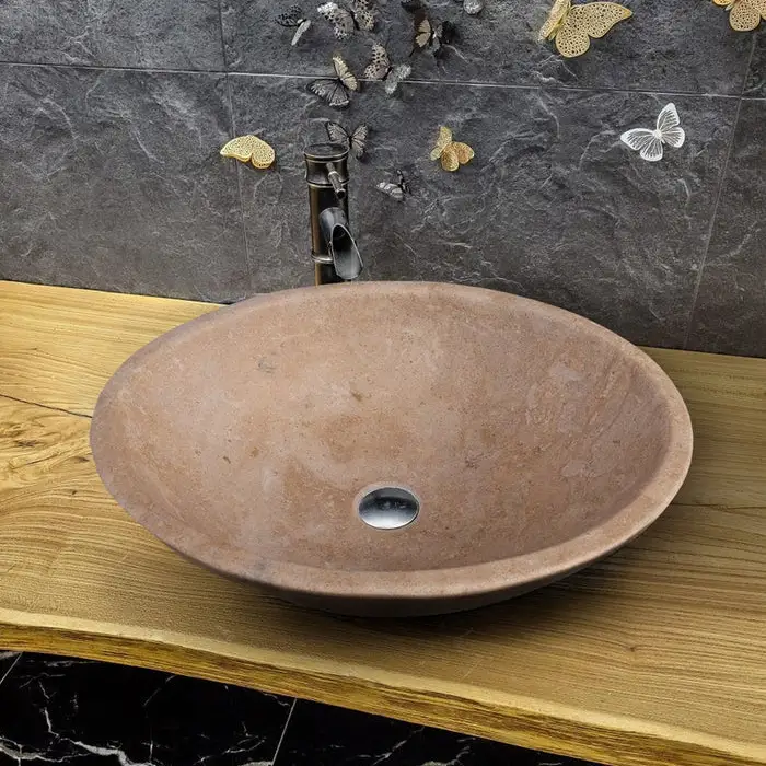 Karina walnut travertine oval vessel sink on wood vanity with tall faucet.