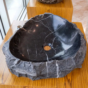 Toros black natural stone marble bathroom sink; rustic oval basin with white veining on wood.