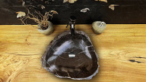 Toros Black natural stone marble rustic above-vanity bathroom sink on a wood countertop with chrome drain