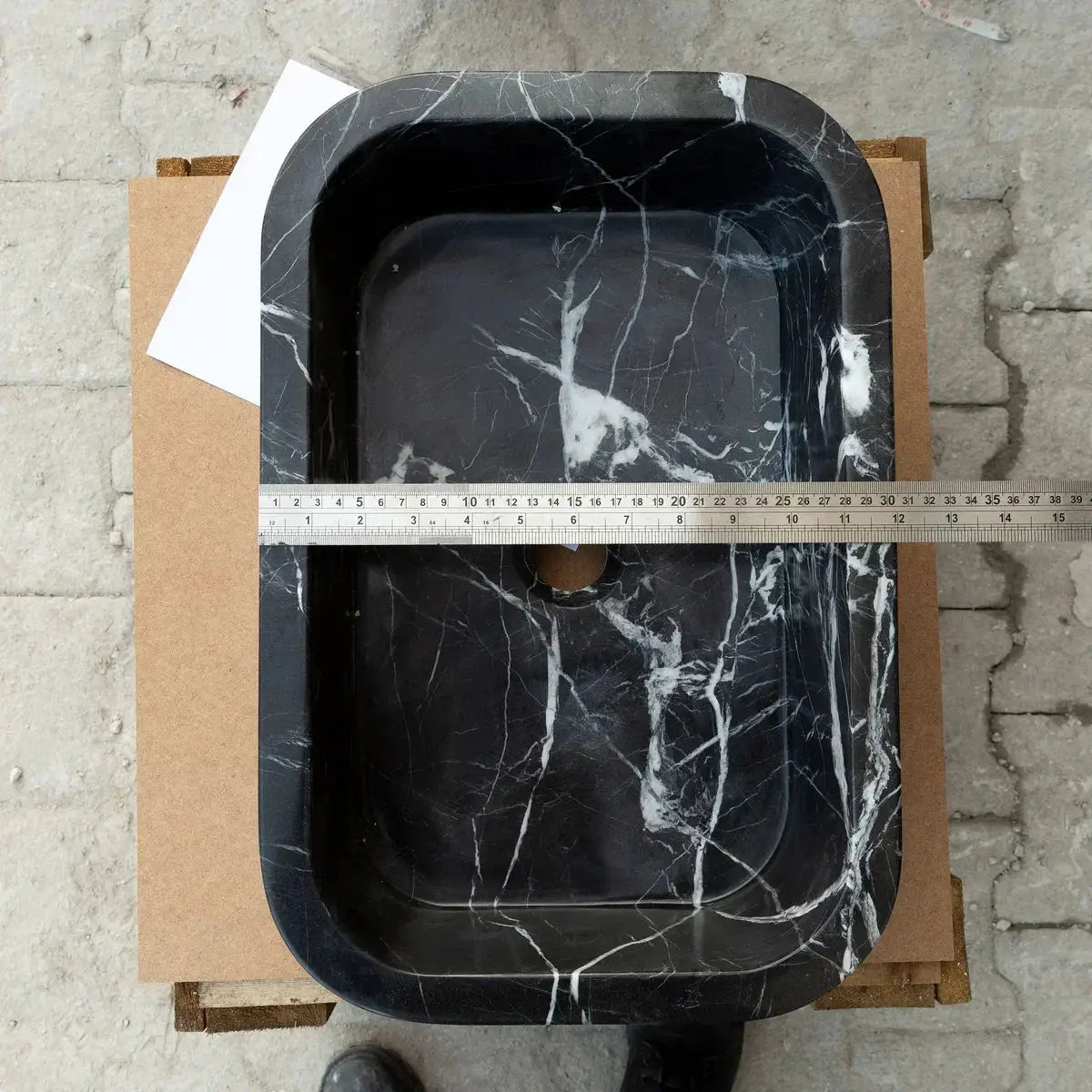 Toros black marble rectangular wall-mount bathroom sink with white veining, viewed from above with ruler for scale.