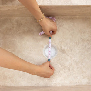 Troia Light Travertine rectangular farmhouse kitchen sink; beige travertine countertop with measuring tape.