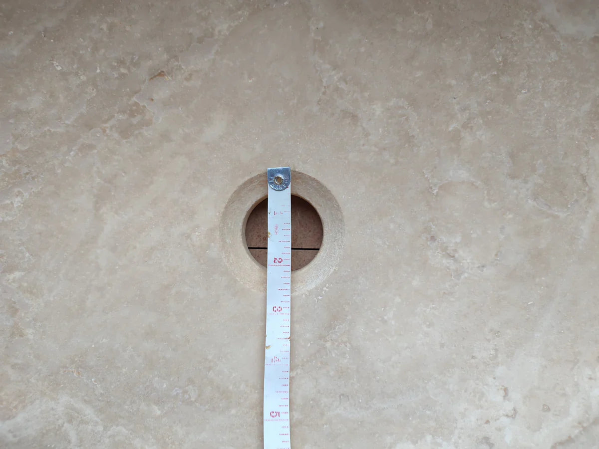 Troia Light travertine bathroom vanity sink cutout on stone countertop with measuring tape