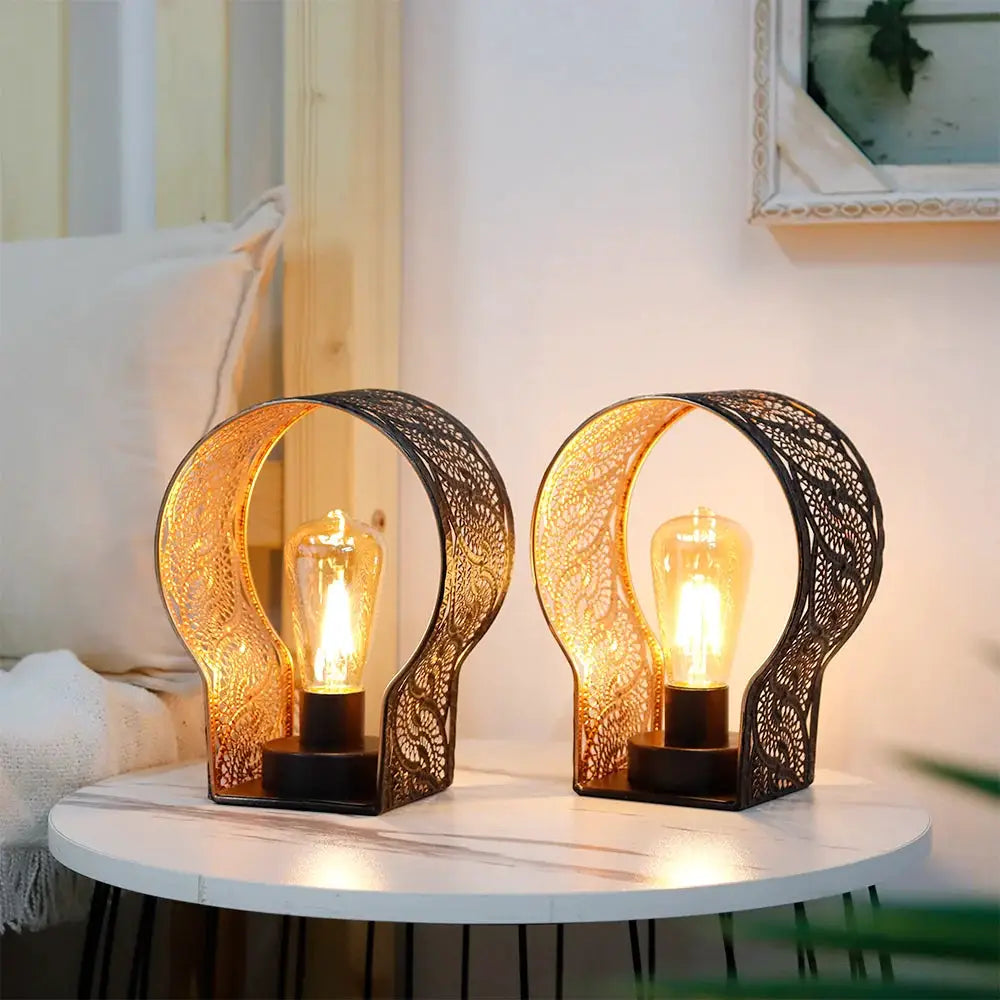 Set of 2 7-inch battery-operated wall-sconce lamps with lace metal arches and Edison bulbs on a round table.