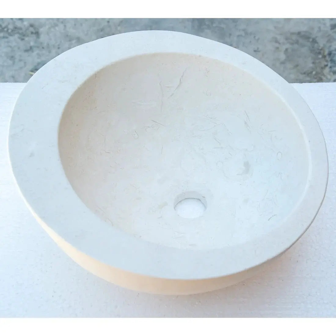 White limestone vanity sink by Villohome with a sloped rim and round bowl