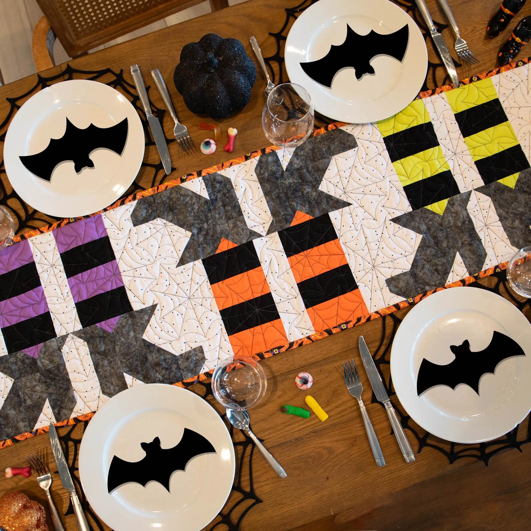 Witches Feet Table Runner Precut Quilt Kit by Block Party Quilt Co; Halloween patchwork runner on table with bat plates