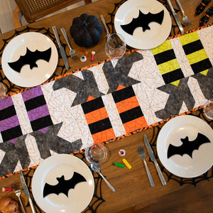 Witches Feet Table Runner Precut Quilt Kit by Block Party Quilt Co; Halloween patchwork runner on table with bat plates