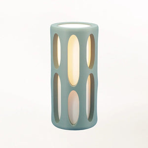 Amoeba Table Lamp, teal sculptural cylinder with vertical oval cutouts and warm interior glow by Terra Labs