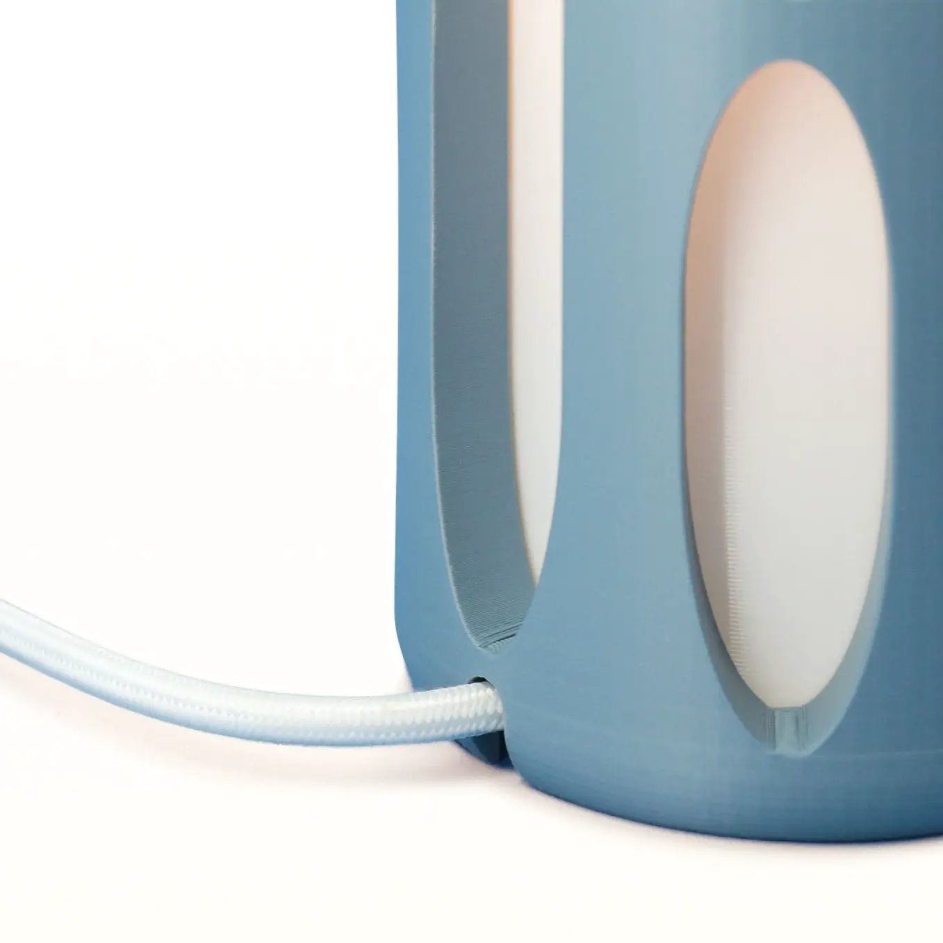 Amoeba Table Lamp by Terra Labs, blue base with white oval cutouts and braided cord.