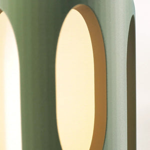 Amoeba Table Lamp by Terra Labs, teal green curved shell with warm light visible through circular openings.