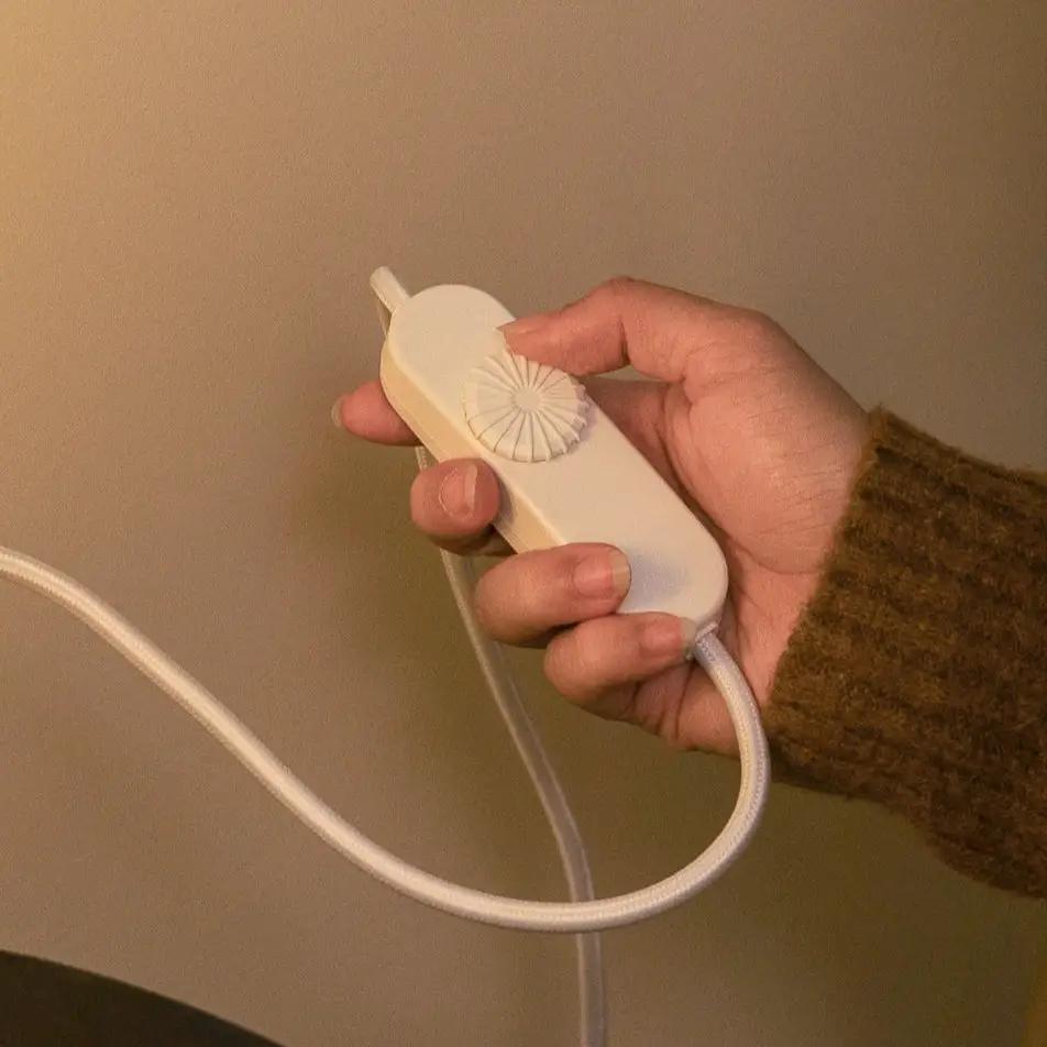 Radiator Table Lamp dimmer control in hand; white plastic with rotary dial and cord