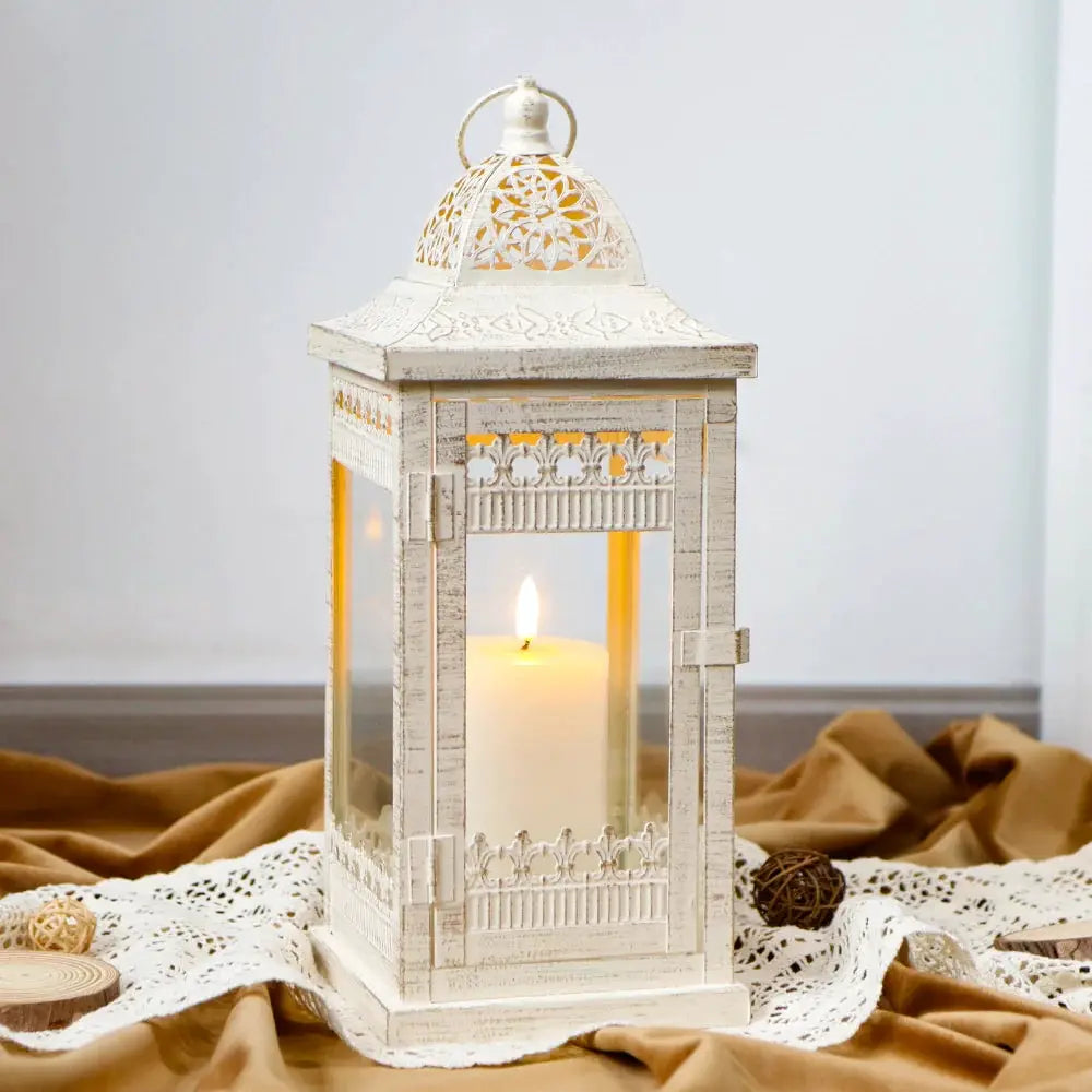 Decorative candle lantern, beige distressed metal with gold brush accents, 14.5in tall with glass panels and lit candle