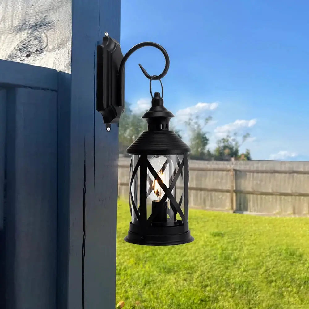 Black metal lantern-style outdoor lamp on a curved wall hook, battery-powered, 10'' tall