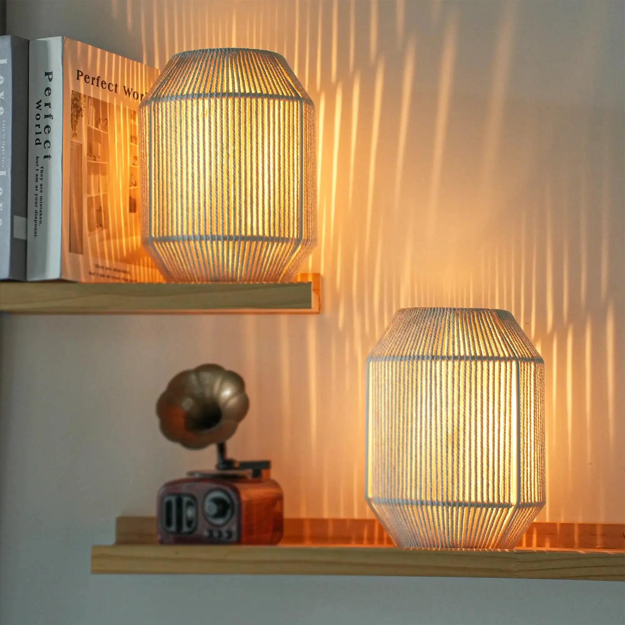 Set of 2 woven shade table lamps with beige tones and warm glow on shelf