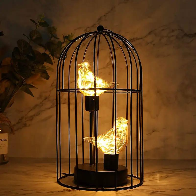 12-inch tall battery-operated birdcage lamp with two glowing bird silhouettes inside a black metal cage.