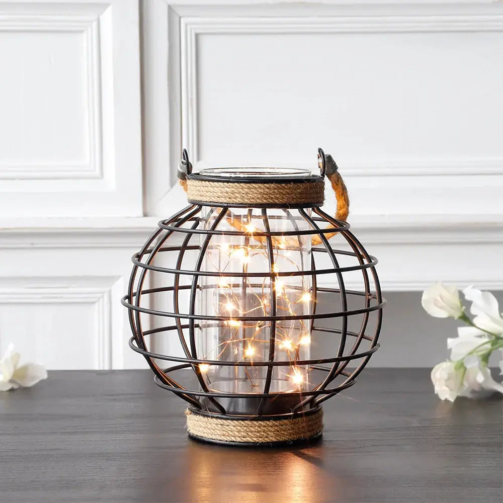 7.3-inch tall battery-powered table lamp with a black metal cage, hemp rope accents and warm fairy lights (JHY DESIGN)