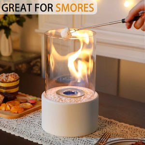 Tabletop fire bowl, 10.5 in tall, with a clear glass cylinder, white base, and white decorative pebbles around the burner.