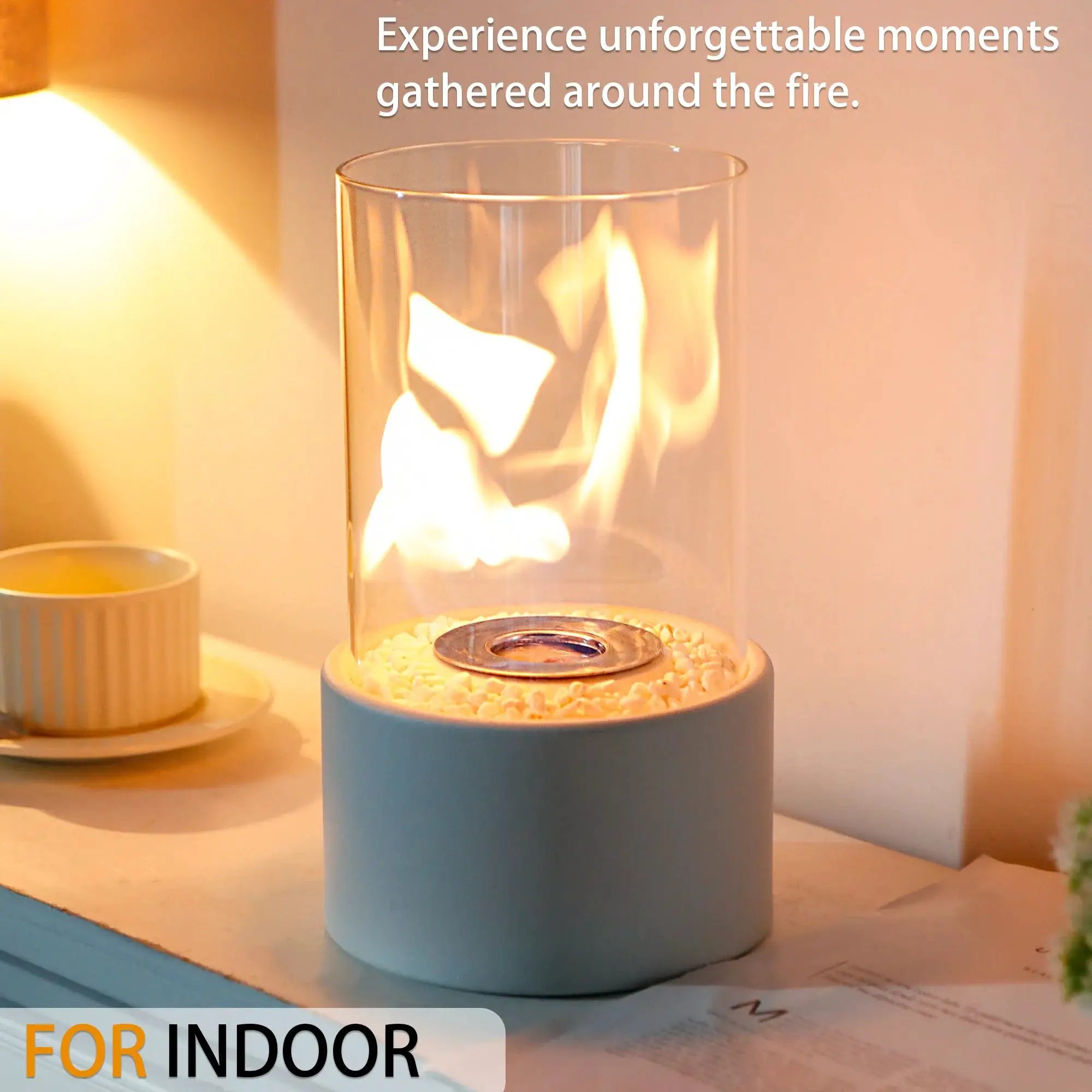 Tabletop fire bowl pot fireplace by JHY DESIGN, glass hurricane with pebble bed and blue base; two items on table.