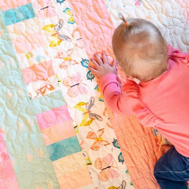 Quilt kit Bricks and Beams Butterflies by Block Party Quilt Co; pastel butterfly fabric quilt laid out.