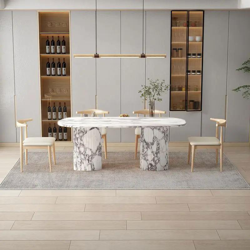 Calacatta Viola marble oval dining table with fluted round legs and 4 light wood chairs in a modern kitchen dining area.