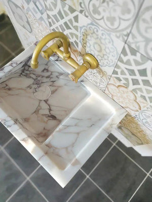 Calacatta Viola marble wall-mount bathroom sink with a gold faucet and gray veining