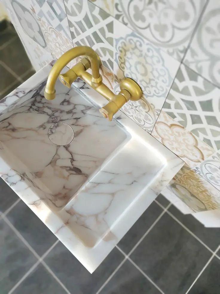 Calacatta Viola marble wall-mount bathroom sink with a gold faucet and gray veining