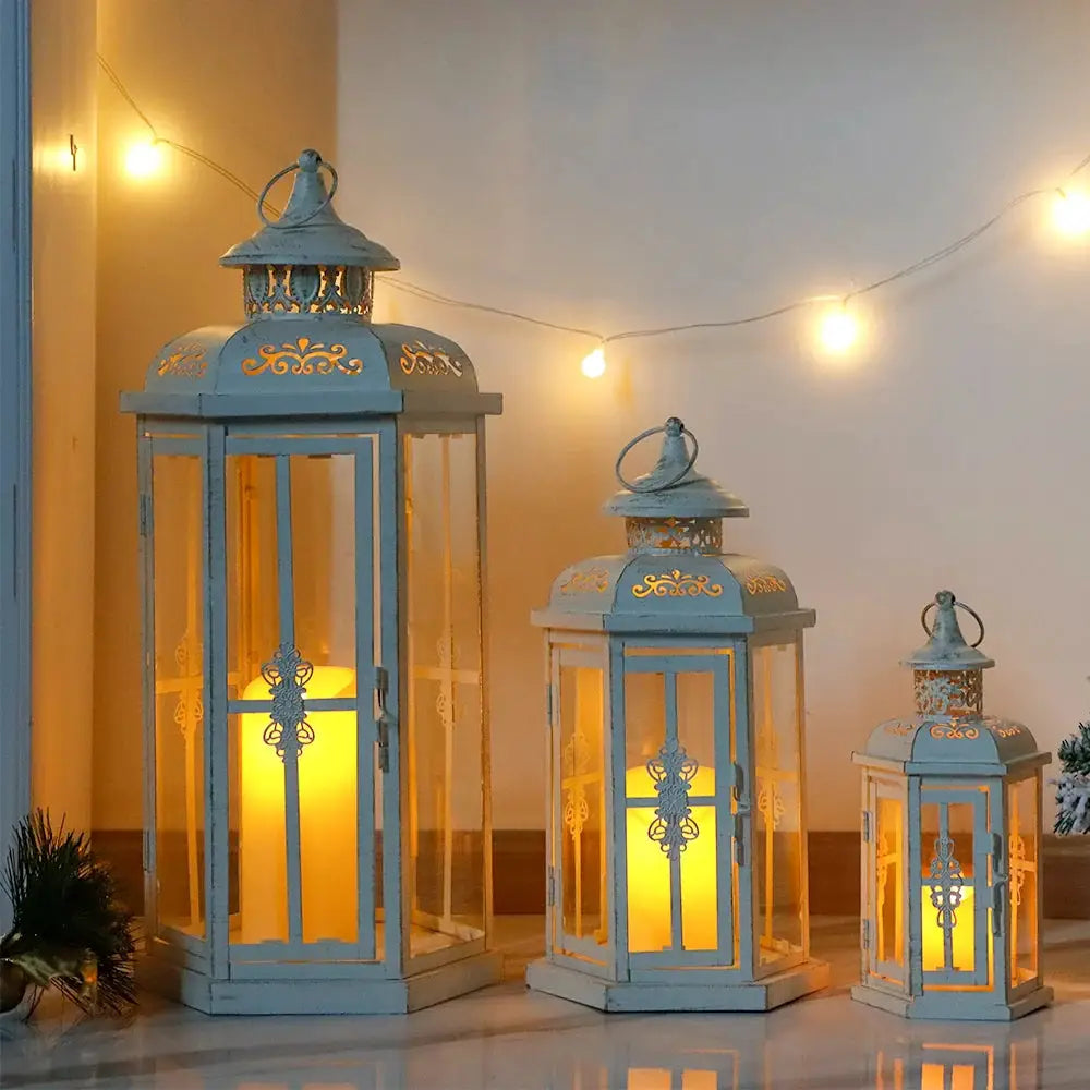 Set of 3 decorative metal candle lanterns in white with gold brush finish, heights 20in, 14in, and 10in.