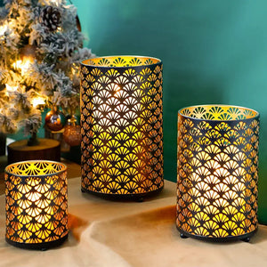 Metal hurricane lanterns set of 3 with intricate cutout pattern; black metal frames and warm yellow glow.
