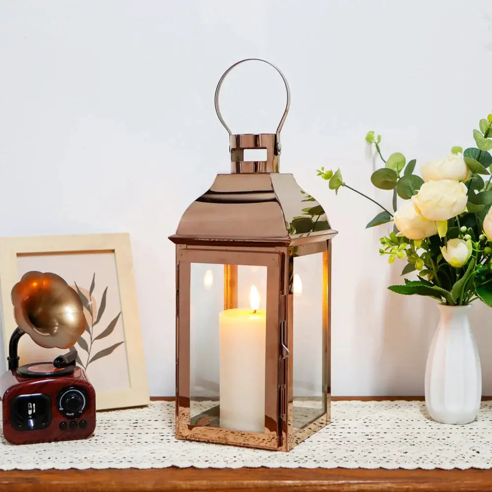 12.5” High decorative lanterns by JHY DESIGN with copper finish, glass panels, and a lit candle inside.
