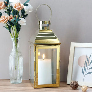 12.5-inch high decorative lantern, gold metal with glass panels and a lit white pillar candle inside