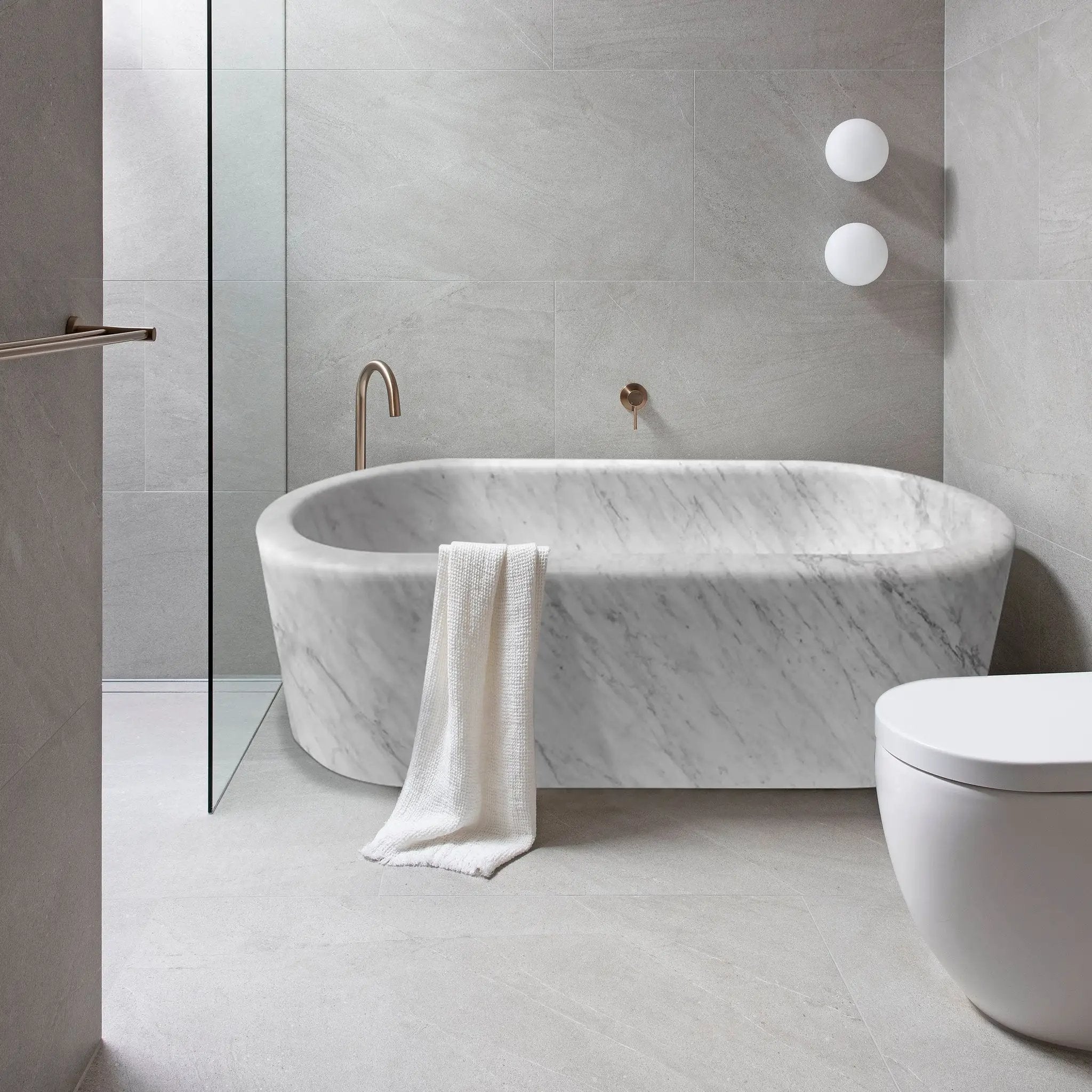 Imperial White Marble Bathtub, hand-carved freestanding tub with copper fixtures in a gray-veined marble bathroom