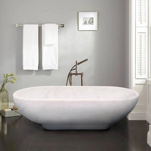 Bianco Carrara white marble freestanding bathtub with copper faucet; two white towels nearby