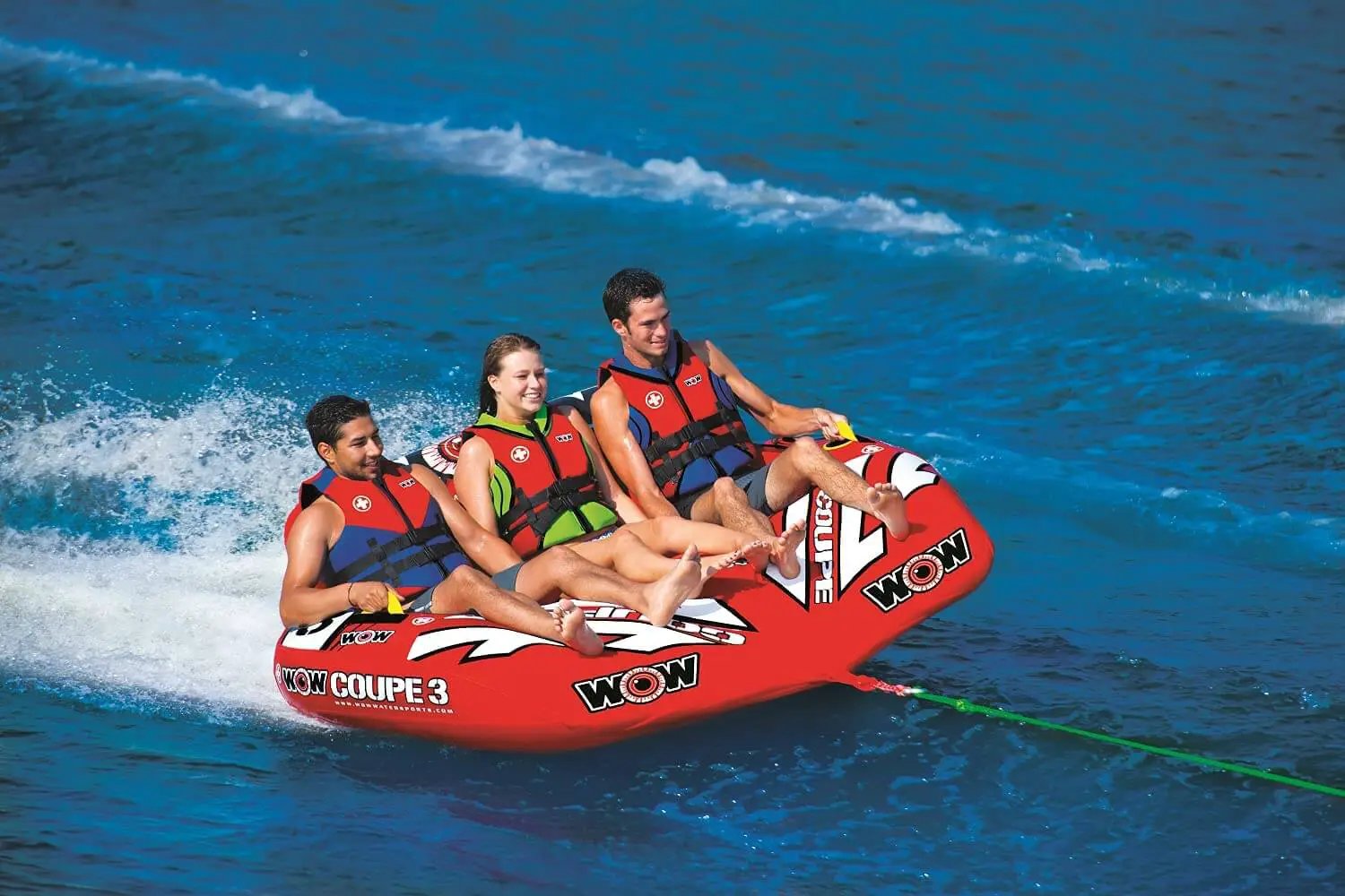 WOW Watersports 3-Person Coupe Cockpit Towable, red inflatable with WOW logos, three riders wearing life jackets.