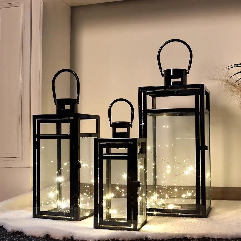 Set of 3 black stainless steel candle lanterns with glass panels and warm string lights