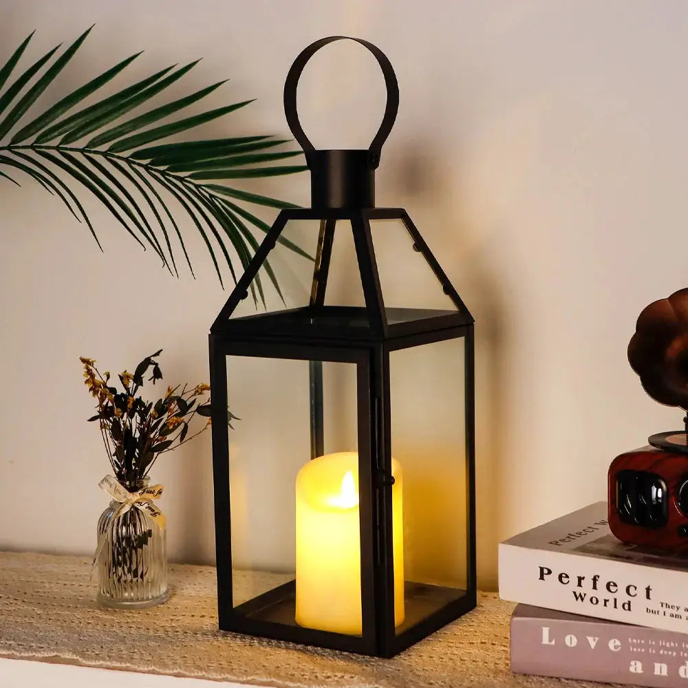 16-inch high black metal decorative lantern with glass panels and a loop handle, housing a warm candle.