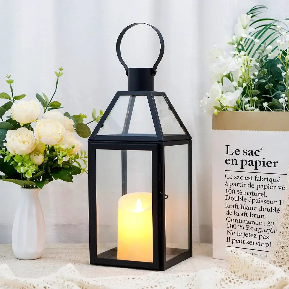 16 inch high black decorative lantern with glass panels and a lit candle inside