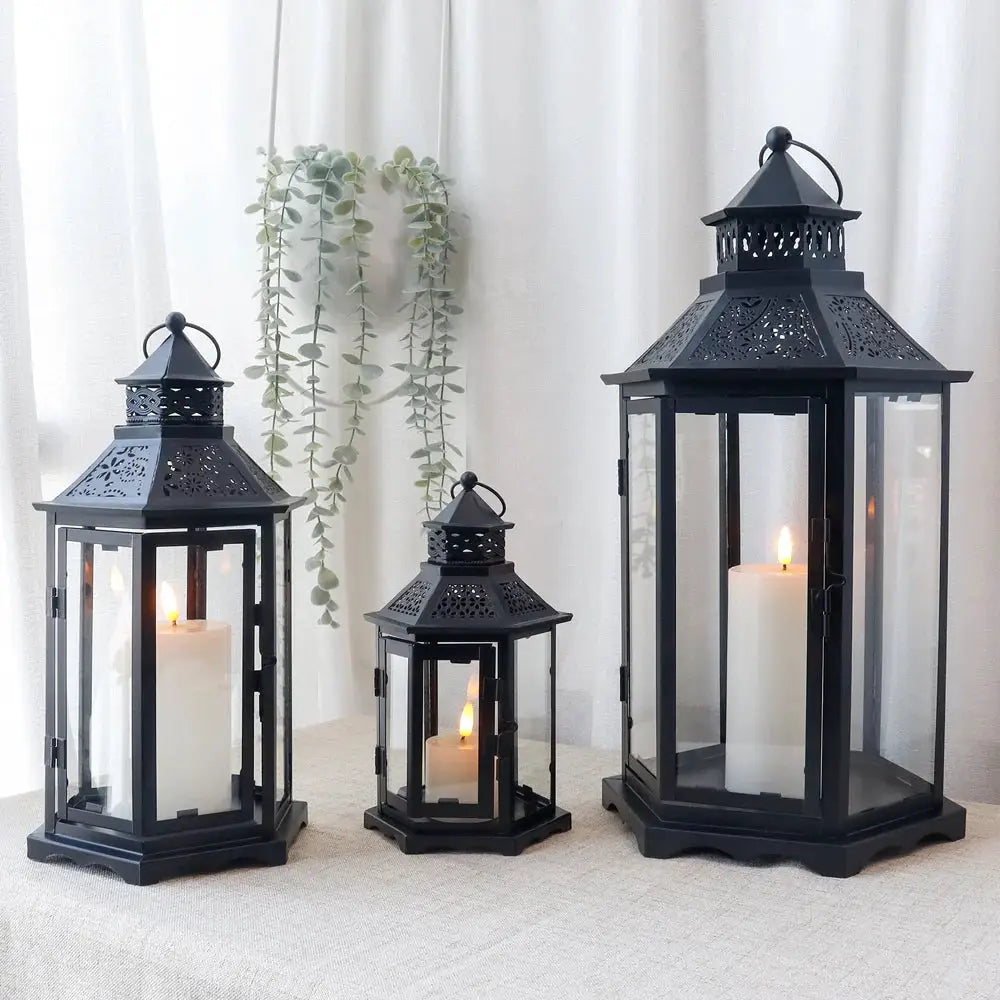 Set of 3 black hexagonal decorative candle lanterns with glass panels and candles inside (18, 13, 10 inches).