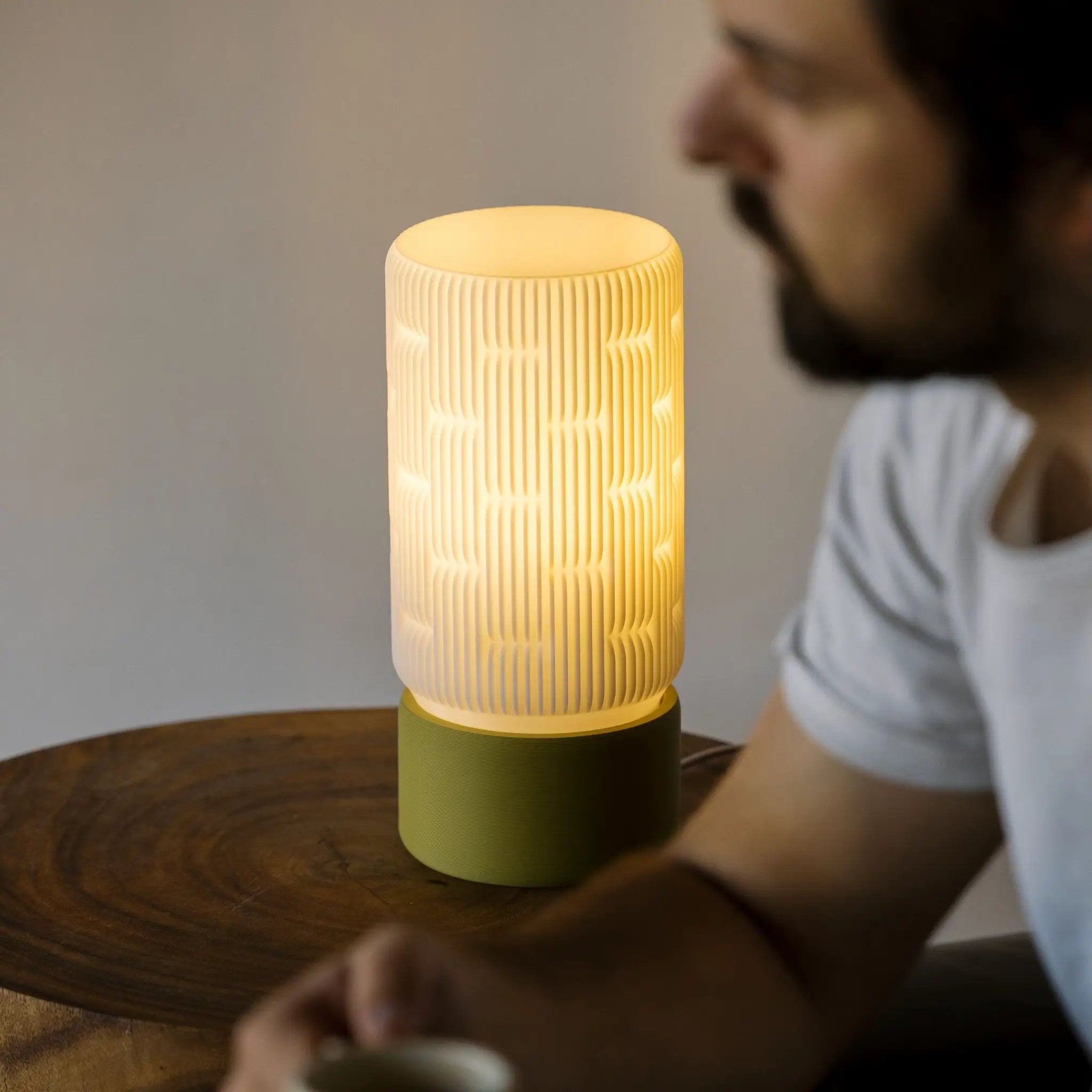 Liunk Table Lamp with ribbed cylindrical shade and green base, emitting warm light.