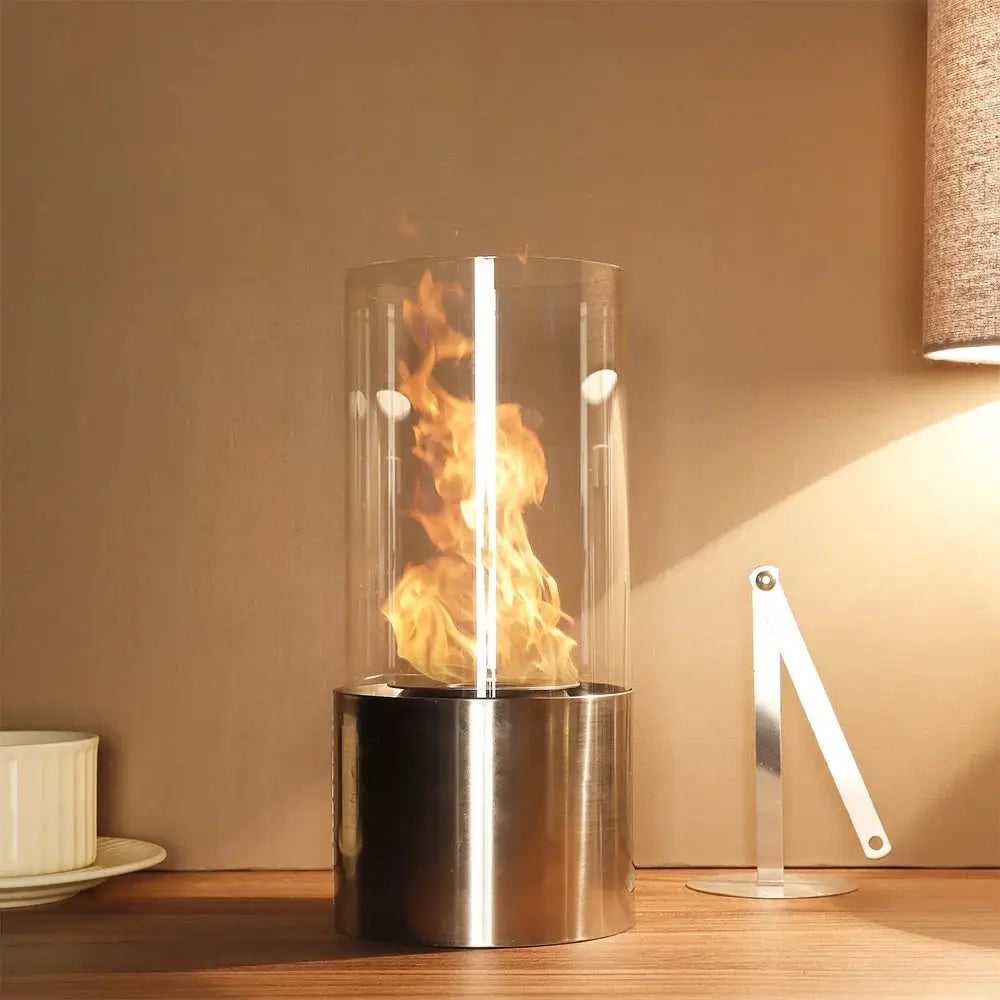 Portable tabletop gel & ethanol fireplace by JHY DESIGN, cylindrical glass flame tube atop a stainless steel base.