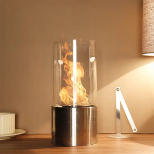 Portable tabletop gel & ethanol fireplace by JHY DESIGN, cylindrical glass flame tube atop a stainless steel base.