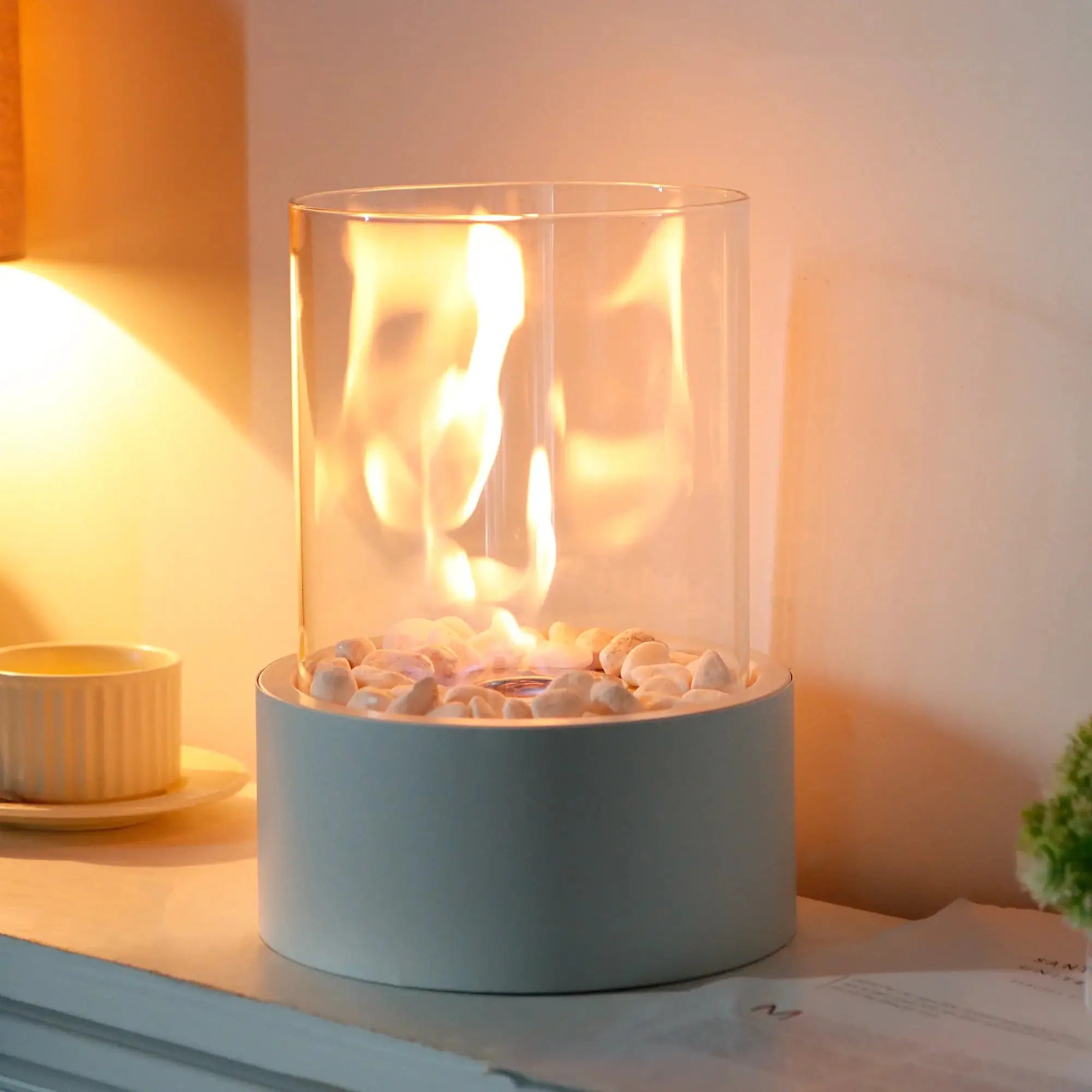 11-inch tall tabletop fire bowl with blue base, clear glass enclosure, and stone bed around the bioethanol flame