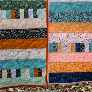 Quilt kit Bricks and Beams Timberline by Block Party Quilt Co featuring teal, orange, and pink patchwork