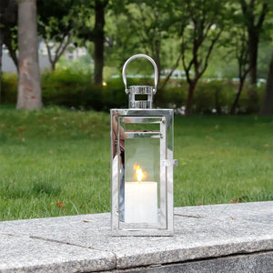 12'' high silver metal decorative candle lantern by JHY DESIGN with glass panes and hanging loop, outdoors.