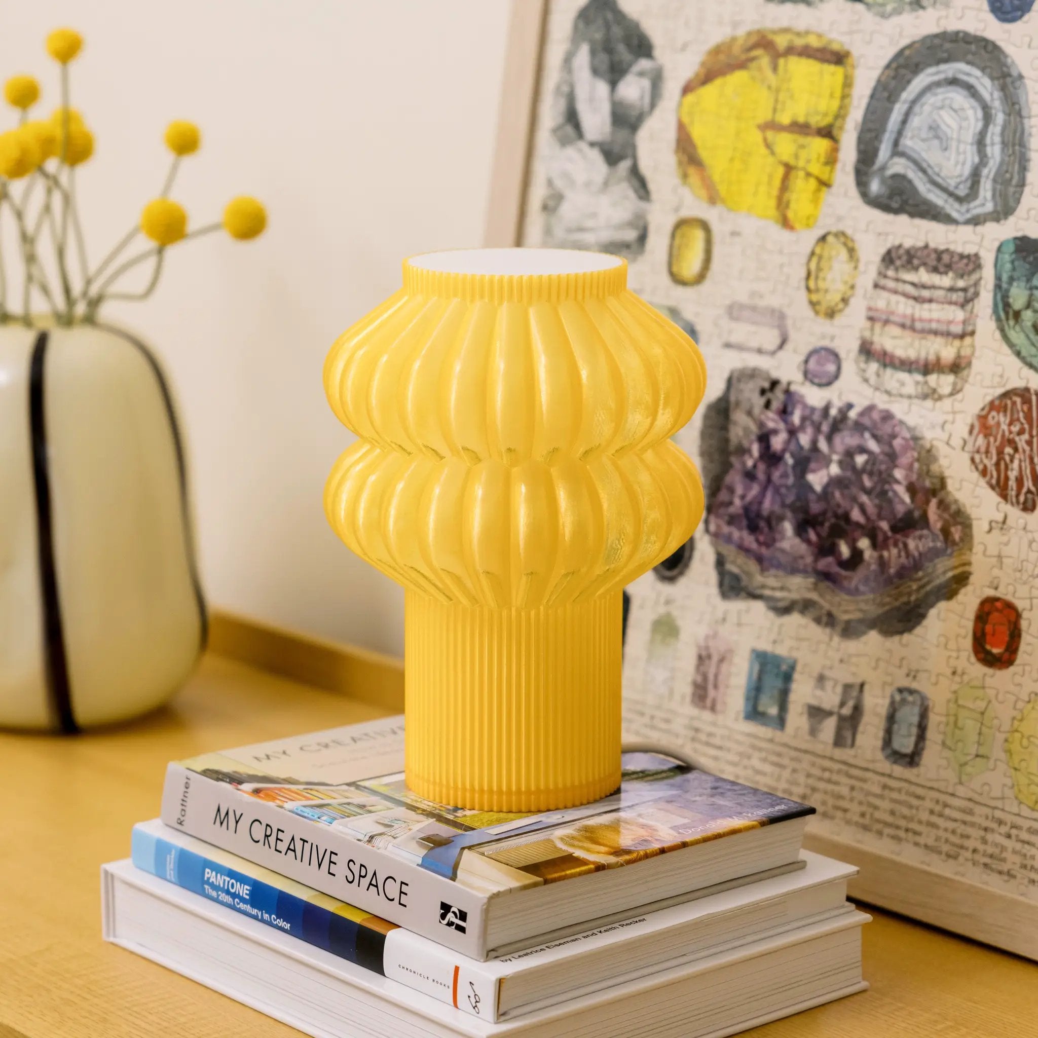 Oppi table lamp in yellow ribbed finish, atop a stack of design books.