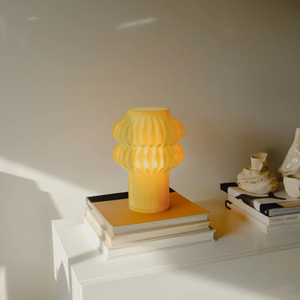 Oppi table lamp by Terra Labs; yellow ribbed design on a stack of books.